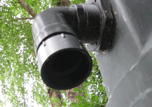 Underside view of an open downspout from a tank