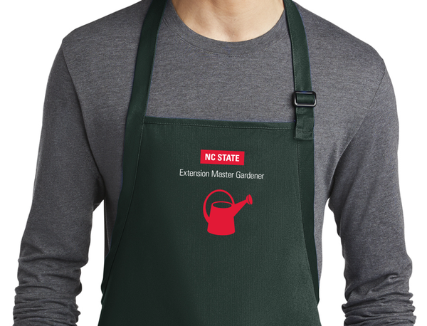 A dark green apron with the vertical logo and the red watering can icon.