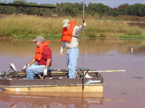 Photo of two people in life vests sampling in small boat