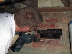 Person in crawlspace cuts access hole to porch