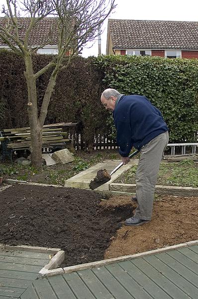 Photo of a man digging in an urban garden.