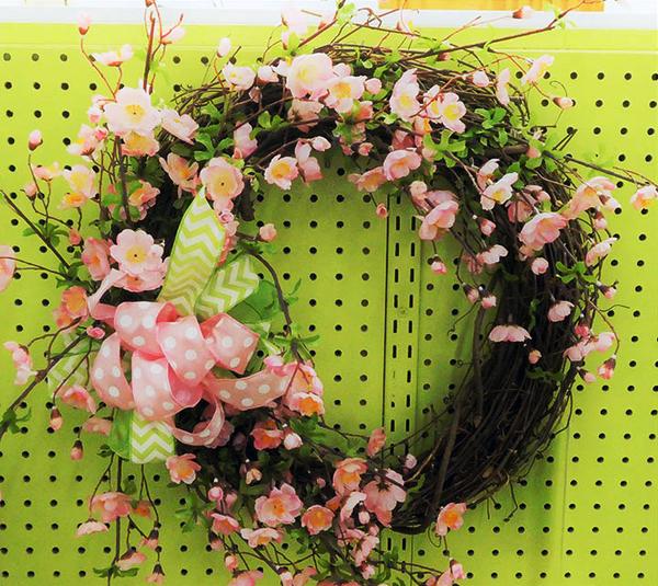 wreath with pink flowers and a bow on a pegboard display