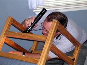 Inspecting the underside of a chair for signs of bed bugs