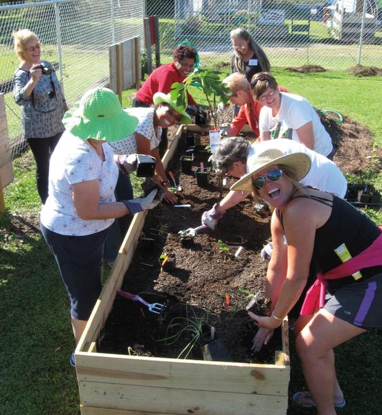 A photo of volunteers preparing a raised-bed planter.