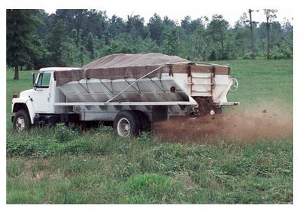 Photo of spreader truck discharging litter onto field