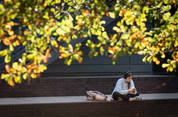 Student looking at phone while wearing headphones