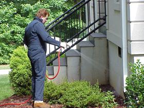 A pest control technician treating the exterior of a house