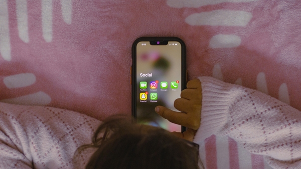 A young person scrolling through their phone screen.
