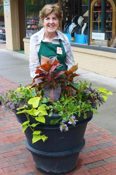 person standing behind large container of plants