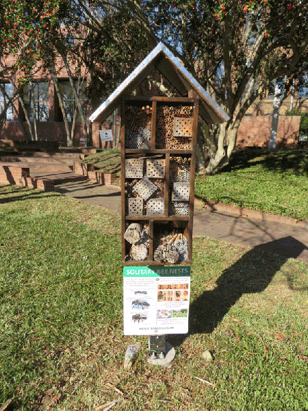 Several bee hotels stacked in sections and covered with a roof.