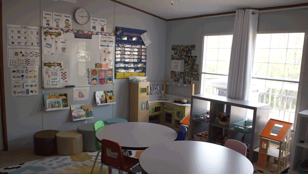 A preschool play area with tables, chairs, a play kitchen, and other toys.