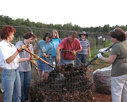 Several people work with a compost pile