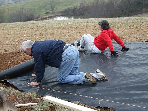 People rolling out landscape fabric