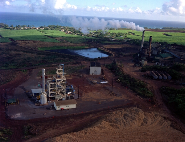 Aerial view of the PICHTR biomass gasification plant with a sugar cane extraction plant in the background and a pile of bagasse in the foreground.