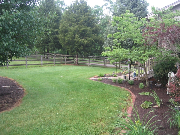 southern yard with lawn and mulched beds. Trees in background.