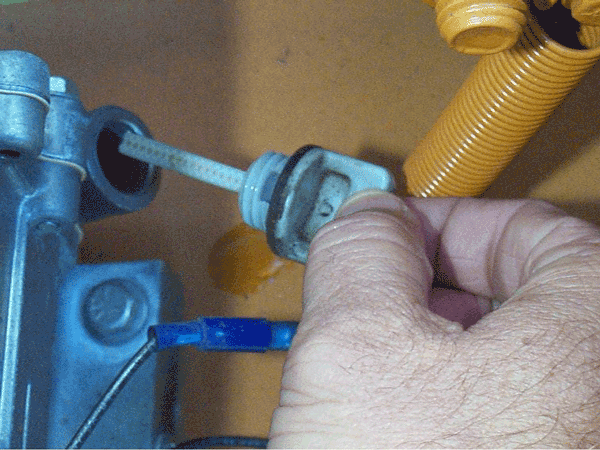 Closeup view of someone checking a small engine oil dipstick.