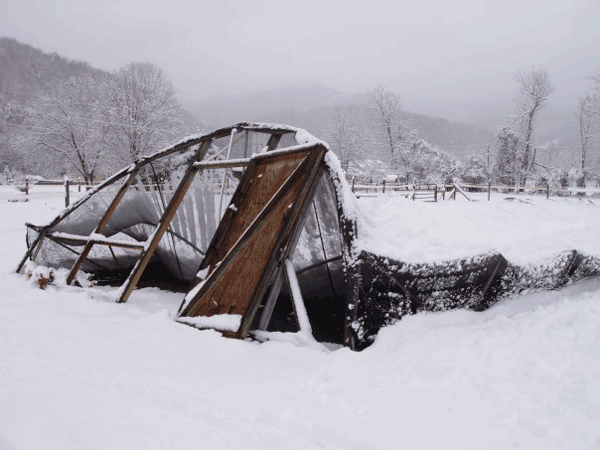 A winter protection house covered with shade cloth that has collapsed