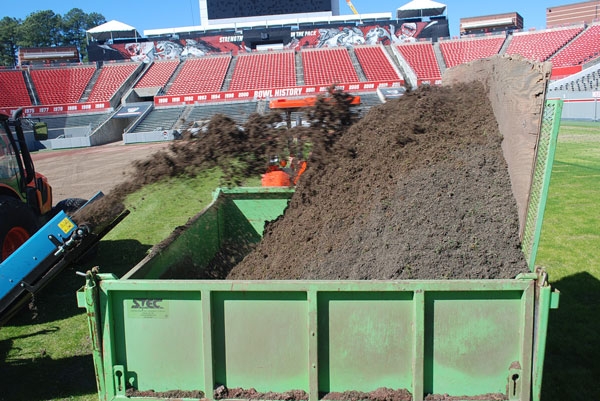 A green trailer collecting debris being generated by a fraise mower.