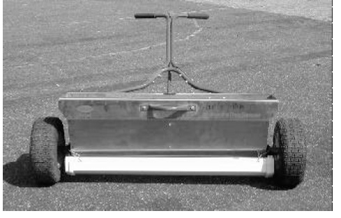 Black and white photo of catch-pan attached to drop spreader