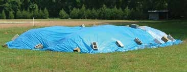 Blue tarp covers pile, weighted down with cinderblocks