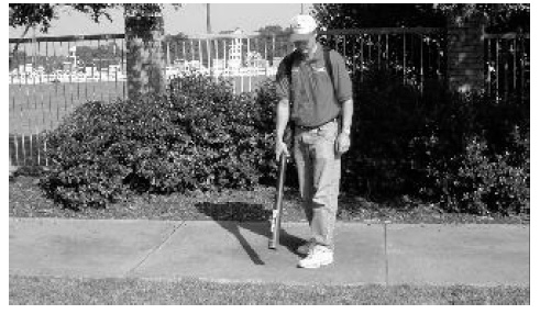 Black and white photo of someone using a leaf blower to clear granules from sidewalk