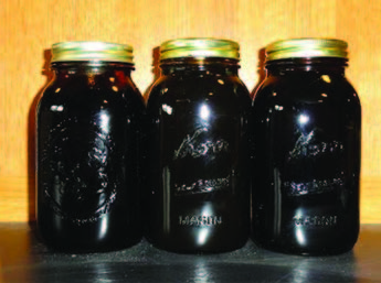 Three jars of dark colored molasses.