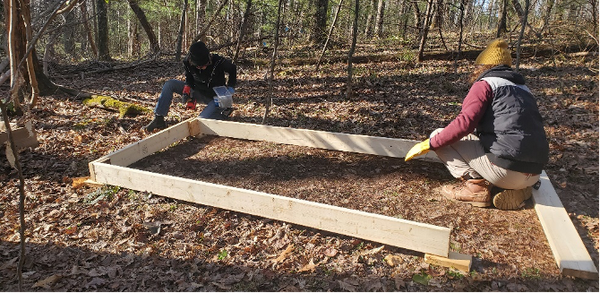 Two people work to attach boards for base of nursery bed
