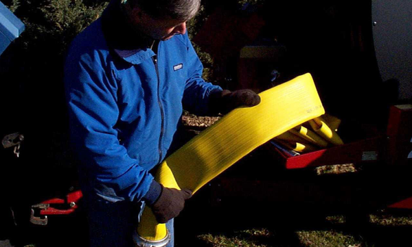 A person checks a large yellow hose.