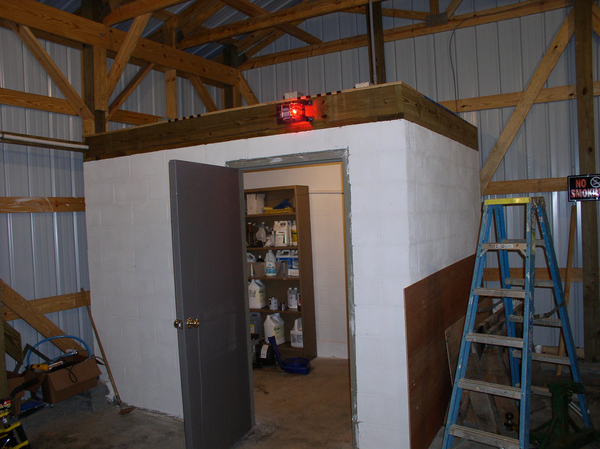 This image focuses on the walls of a small room with an open door inside a pesticide building. Inside the lighted room, shelves stocked with pesticide containers are visible.