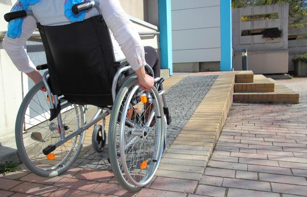 A wheelchair user heads up the ramp toward a building entrance