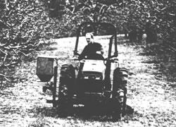 Black and white photo of a person using a tractor and applying rodenticide